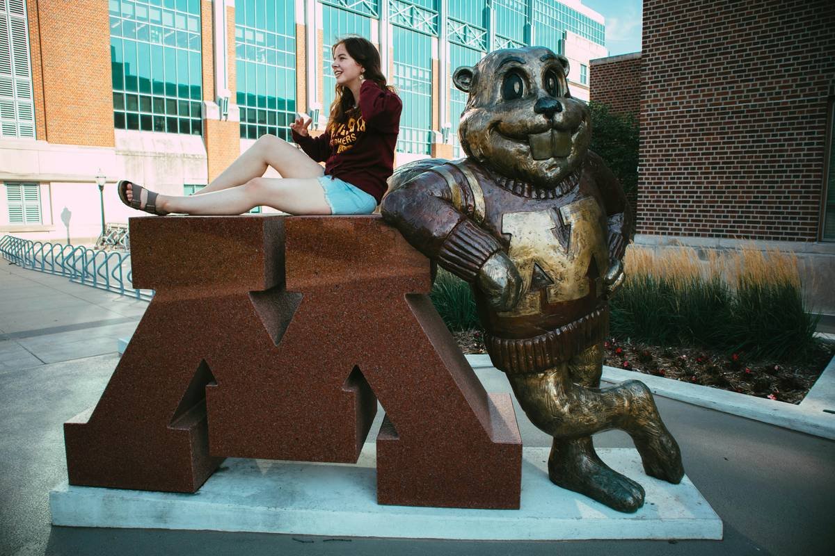 a woman sitting on top of a statue of a bear